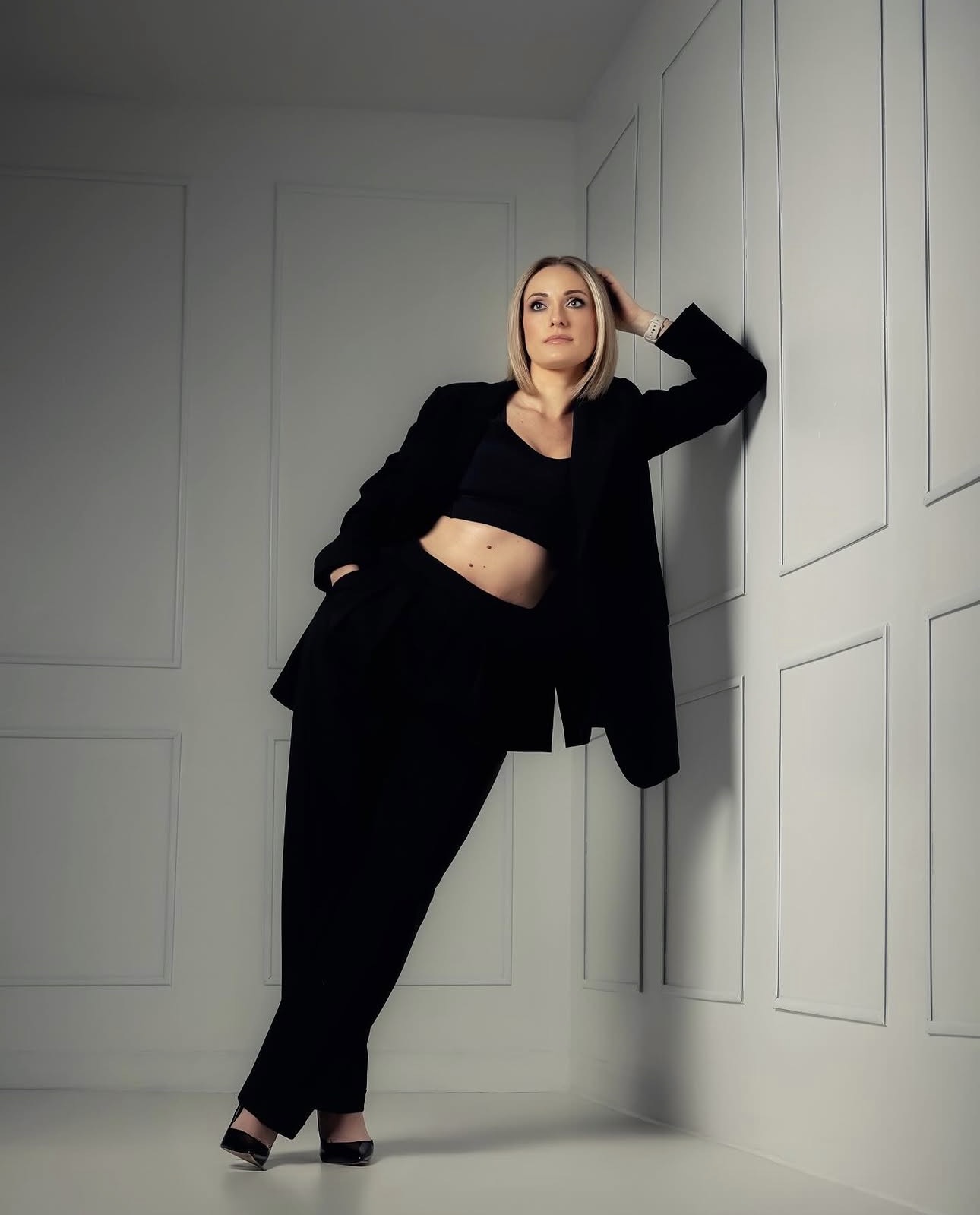 Tailored black suiting against a panelled wall