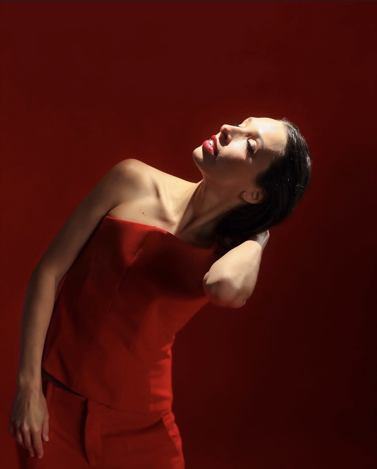 A red gown arched against deep red