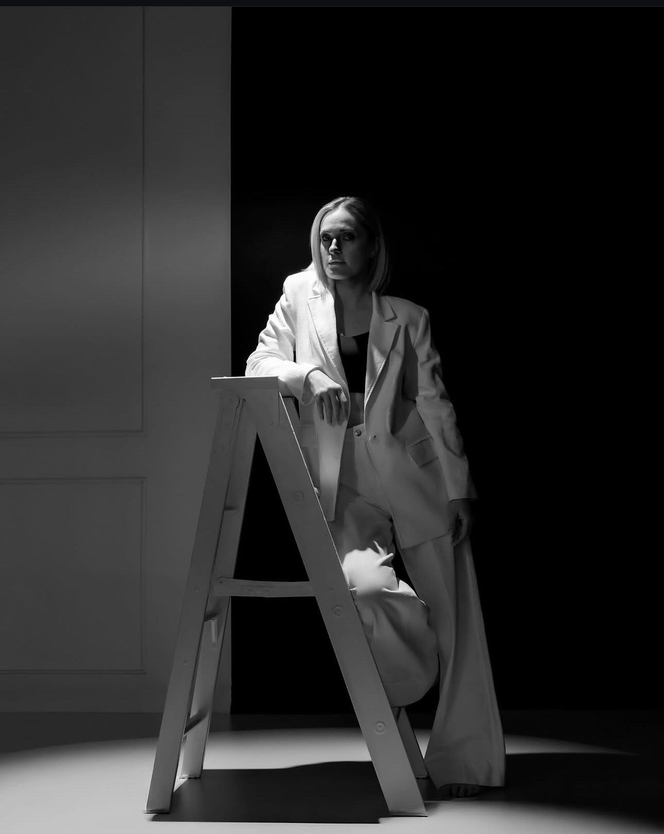 Black and white — a figure on a step ladder against black