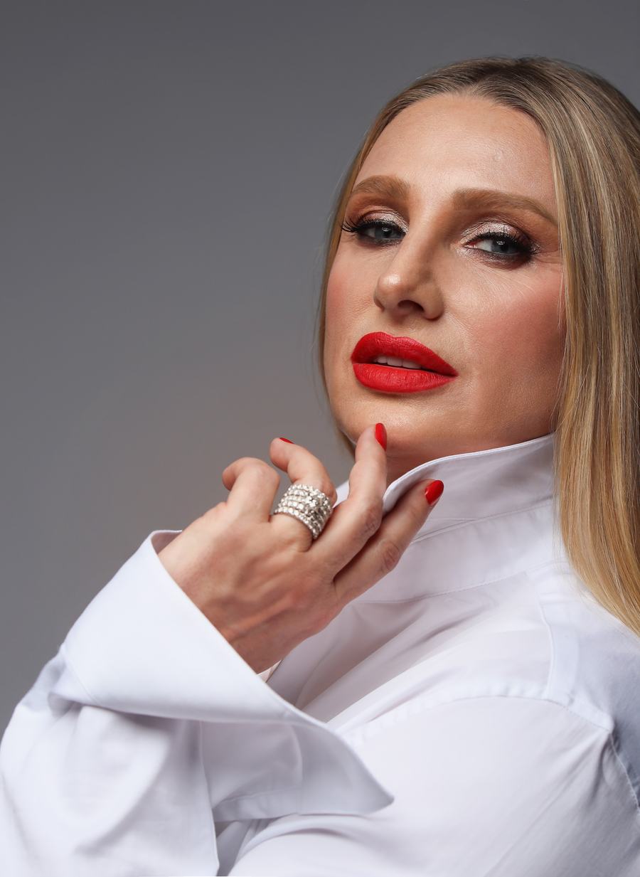 Red lips and a white shirt collar, a hand raised with a crystal ring