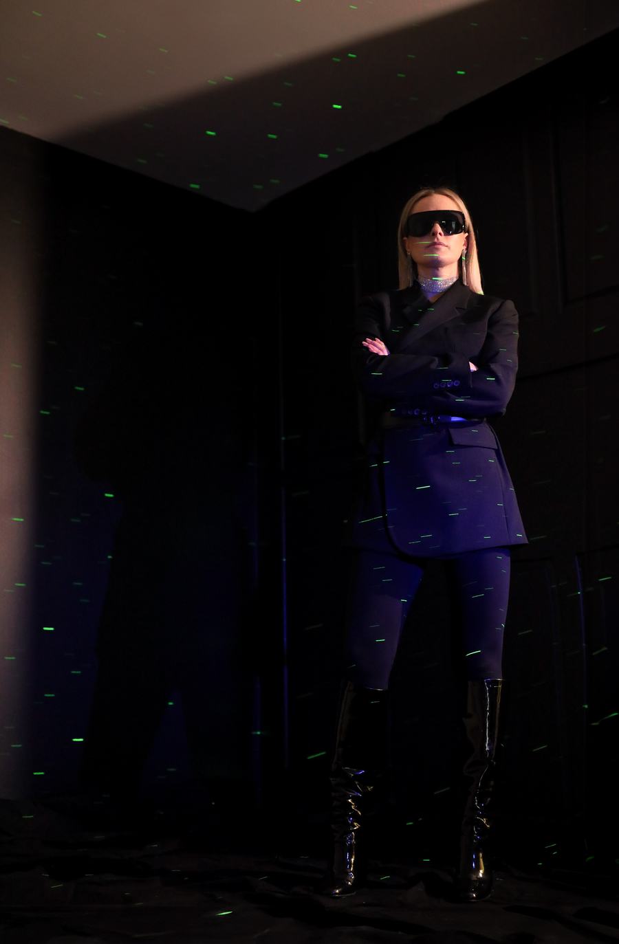 A tailored suit and thigh-high boots in a dark room scattered with green light