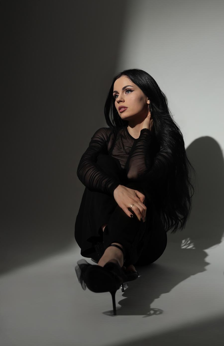 Black sheer sleeves on a grey floor, cut by a hard diagonal of light