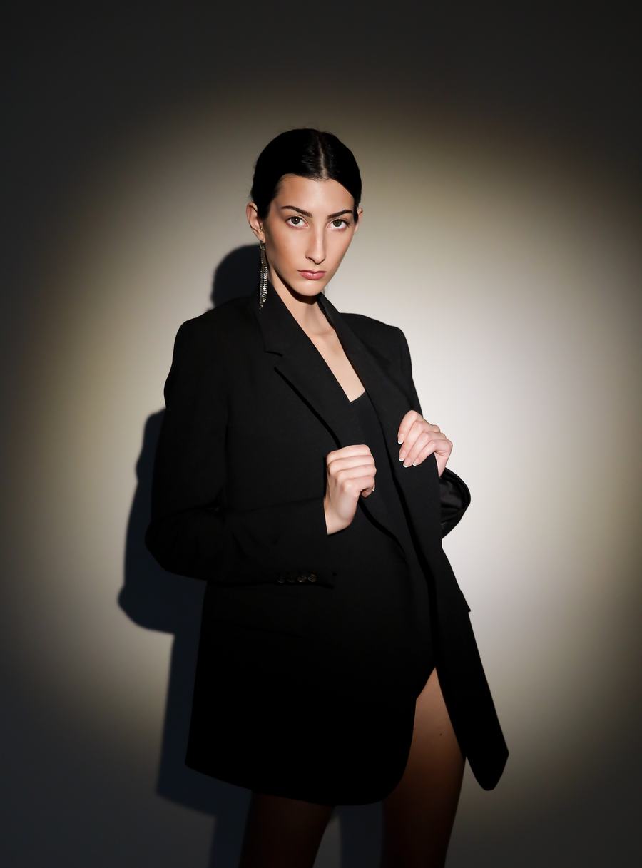 An oversized black blazer held closed in a ring of light