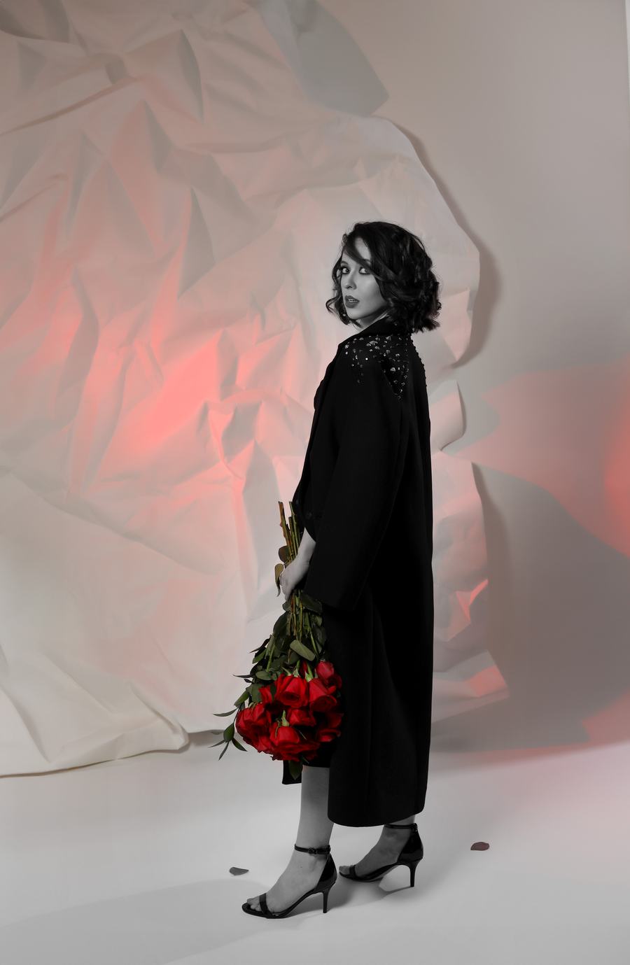 Black and white with red roses — a long coat against crumpled paper