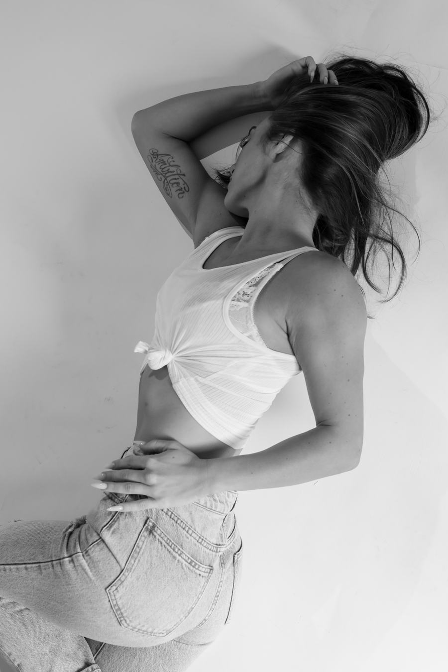 Black and white — reaching back into her hair, in a knotted white top