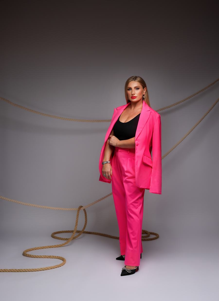 A hot-pink suit against grey, a coil of rope at her feet