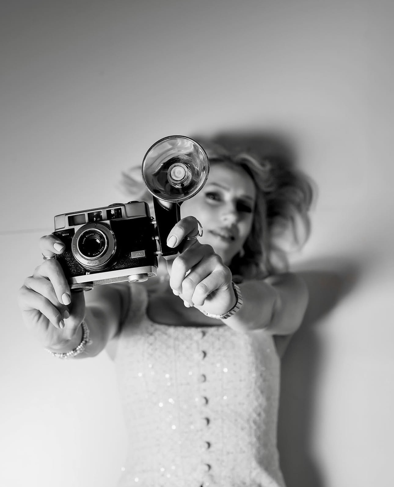 Portrait of Liliya Ushin holding a vintage camera toward the viewer